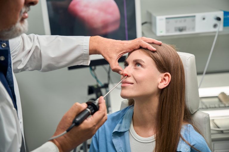 Adult otolaryngologist carefully inspects the patients eye using a medical examination tool in the clinic