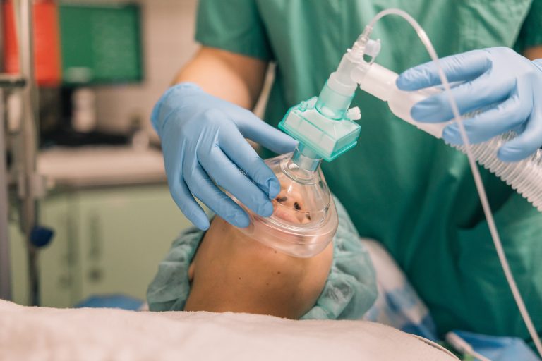 Close-up of a medical worker assisting a patient with a ventilation mask, emphasizing the importance of respiratory care in medical treatments